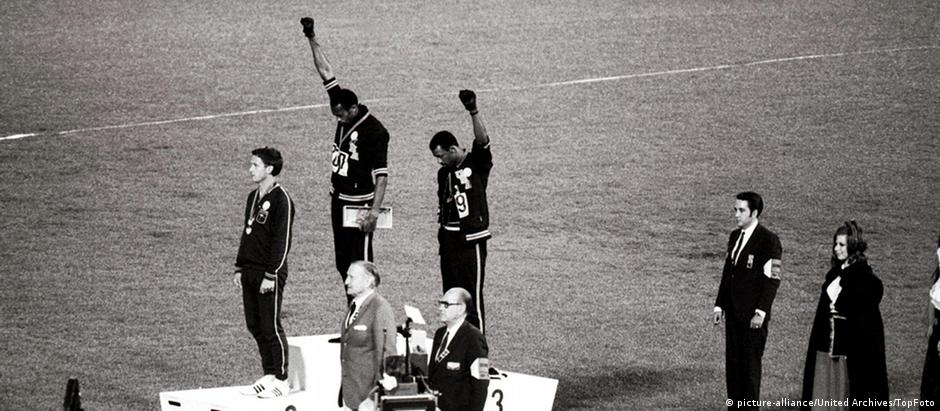 Tommie Smith e John Carlos fazem o gesto dos Panteras Negras. Australiano Norman, à frente, os apoiou