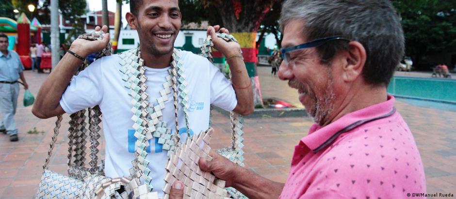 Jesus Campos vende suas bolsas confeccionados a partir de bolívares venezuelanos numa praça pública na Colômbia